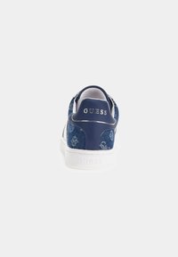 Mörkblå denim sneakers med vit sula, med en texturerad ovandel och metallisk logotyp på hälen, dekorerade med mönstrad detalj.