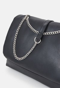 Schwarze Lederhandtasche mit silberner Kettenriemen, mit glatter Textur, abgerundeter Form und Klappverschluss.