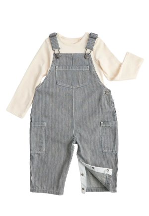 Camicia crema a manica lunga con salopette a righe bianche e nere con tasca frontale, bottoni laterali e chiusure a scatto su una gamba.