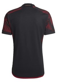 Mustapohjainen urheiluasu, jossa on punaiset gradienttisivustat ja kaulusyksityiskohta. "DEUTSCHLAND" -teksti selkäpuolella lähellä kaulaa. Lyhyet hihat.