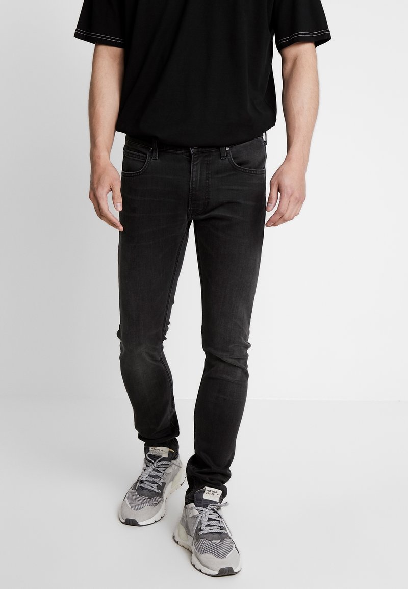 Svarta jeans i denim med smal passform, med en klassisk femficksdesign och subtila sömmar. Matchas med gråa sportskor.