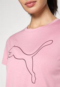 Rosa bomull T-skjorte med en stor brun Puma-logo trykket på forsiden. Designet har rund halslinning og korte ermer.