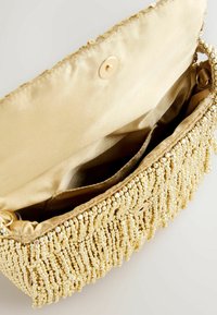 Goldene Perlen-Clutch mit fransigen Akzenten, satinierter Innenseite, zwei Fächern und einem magnetischen Druckverschluss. Futter aus glattem Stoff.