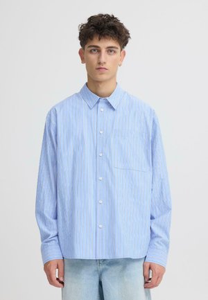 Hellblaues langärmeliges Hemd mit dünnen vertikalen weißen Streifen, durchgeknöpft mit ausgestelltem Kragen und einer einzelnen Brusttasche. Legere Passform.