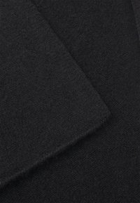 Deux morceaux de tissu noir foncé qui se chevauchent, présentant une texture douce avec une surface légèrement duveteuse, arborant une apparence uniforme et lisse.