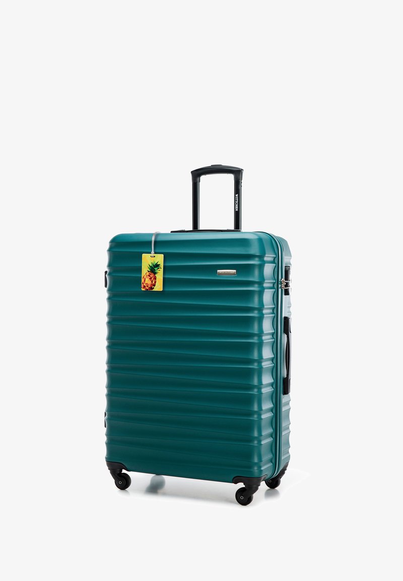 Tyrkysový tvrdý kufr s rýhovaným povrchem, černými kolečky a teleskopickou rukojetí. Obsahuje připojenou žlutou visačku ve tvaru ananasu.