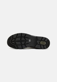 Black rubber sole with patterned tread, featuring deep grooves and a textured surface for traction. Includes embossed brand detail and size indicator.