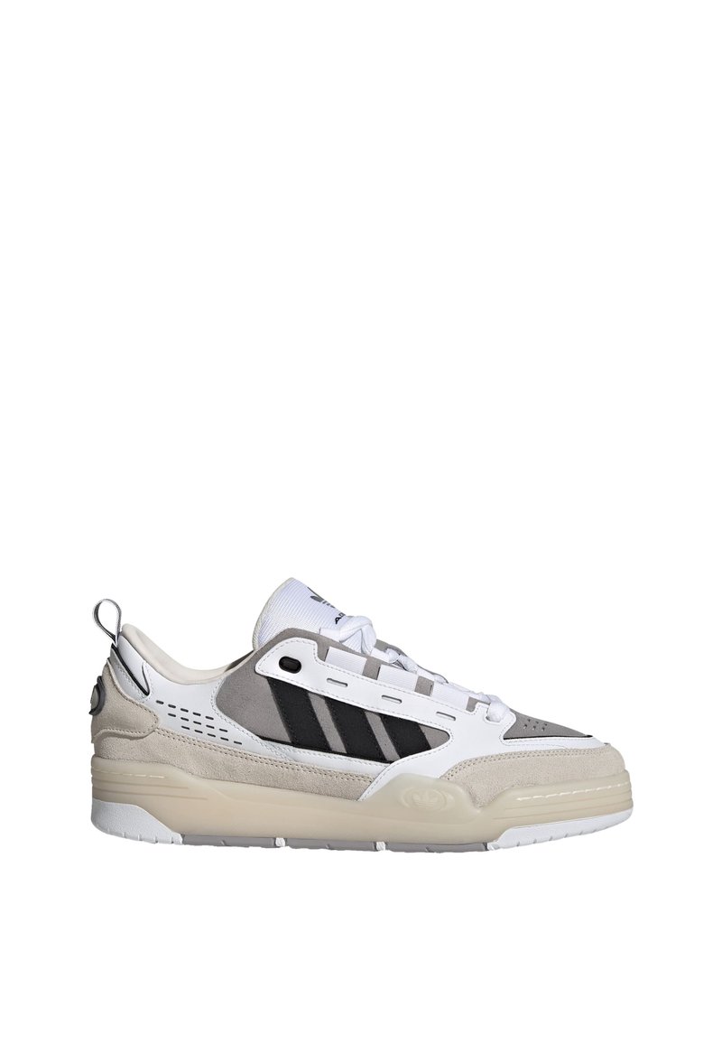 Sneakers z białą skórzaną cholewką i szarymi zamszowymi detalami. Posiada czarne paski, wentylowane boki i grubą przezroczystą podeszwę.