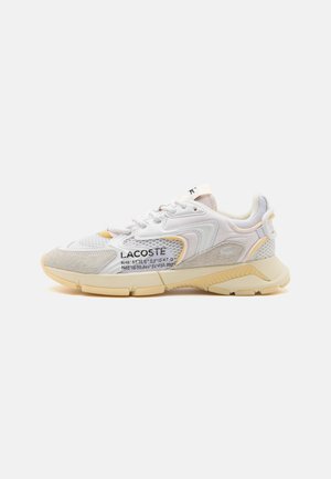 Weißer und beiger Lacoste-Sneaker mit Mesh- und Wildlederdetails, Markenlogo und aufgedruckten Koordinaten an der Seite, in der Seitenansicht gezeigt.