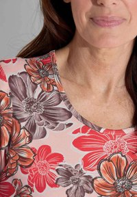 Bloemmotief top met een ronde halslijn, versierd met grote rode, oranje en grijze bloemen op een zachte roze achtergrond, met eentextuurstof.