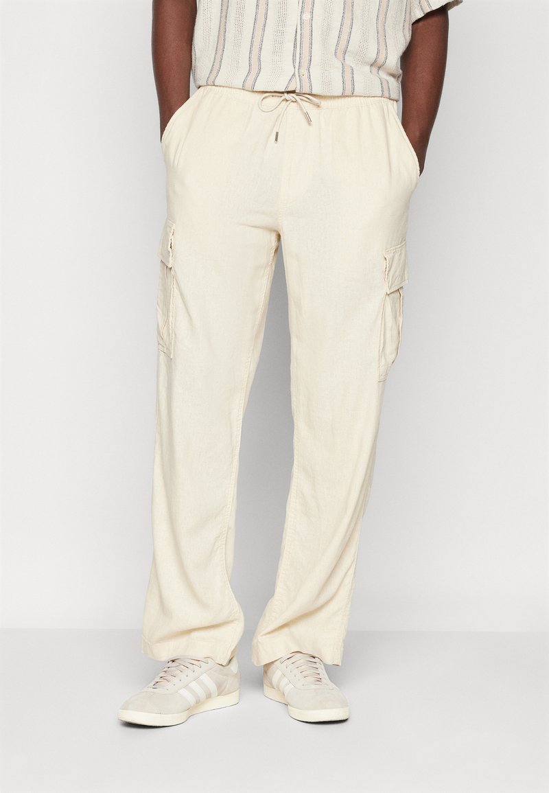 Creme-kleurige cargobroek met een trekkoord in de taille, twee zijzakken en een ontspannen pasvorm, gemaakt van lichtgewicht stof.