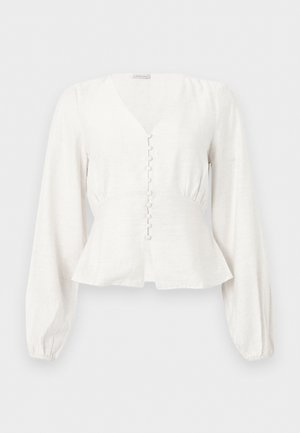 Λευκό μακρυμάνικο μπλουζάκι με V-λαιμόκοψη, εφαρμοστή μέση, κουμπιά καλυμμένα με ύφασμα στο μπροστινό μέρος και ελαφρώς φαρδύ τελείωμα σε απλό φόντο.