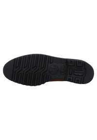 Semelle de chaussure en caoutchouc noir avec un motif de traction texturé, arborant un logo et un design d'accent près de la zone du talon.