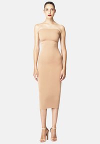 Abito midi aderente senza spalline in tessuto stretch nude con texture liscia e forma contornata, abbinato a sandali con tacco beige.