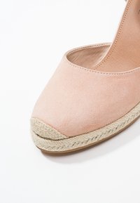 Pink suede espadrille with a rounded toe and a woven jute sole. The upper has a smooth texture, and the design is slip-on style.