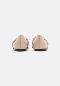 Bailarinas de charol en rosa pálido con punta redondeada, detalladas con acentos metálicos a lo largo de los lados y una suela negra.