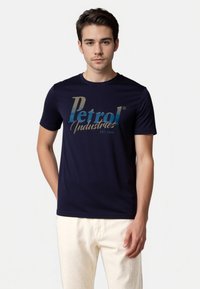 Marineblå T-shirt med "Petrol Industries" logo i gradient guld- og blå skrift. Blødt bomuldsstof, rund hals, tætsiddende design.
