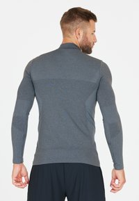 Langærmet atletisk skjorte lavet af struktureret grå stof med tætsiddende design, har ribbede detaljer på ærmerne og ryggen samt en høj krave.