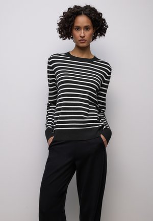 Svartvit randig tröja med rund hals, långa ärmar och ribbade muddar. Matchad med svarta, löst sittande byxor.