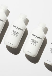 Witte plastic flessen shampoo met zwarte tekstlabels. Elke fles heeft een ronde vorm en een flip-top deksel, gerangschikt in een rij.