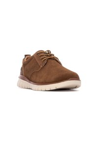 Zapatos de ante marrón con cordones, con punta redondeada y una suela gruesa y acolchada blanca. Presenta detalles en piel marrón y cordones color crema.