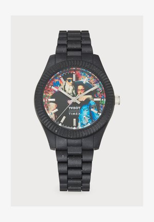 Montre en caoutchouc noir avec un cadran à motifs audacieux présentant des œuvres d'art et des accents argentés. Boîtier rond avec lunette embossée et bracelet maillé.