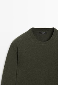 Maglione lavorato a maglia verde scuro con scollatura a girocollo, caratterizzato da una texture morbida e delicate dettagli a costine attorno al colletto e ai polsini.