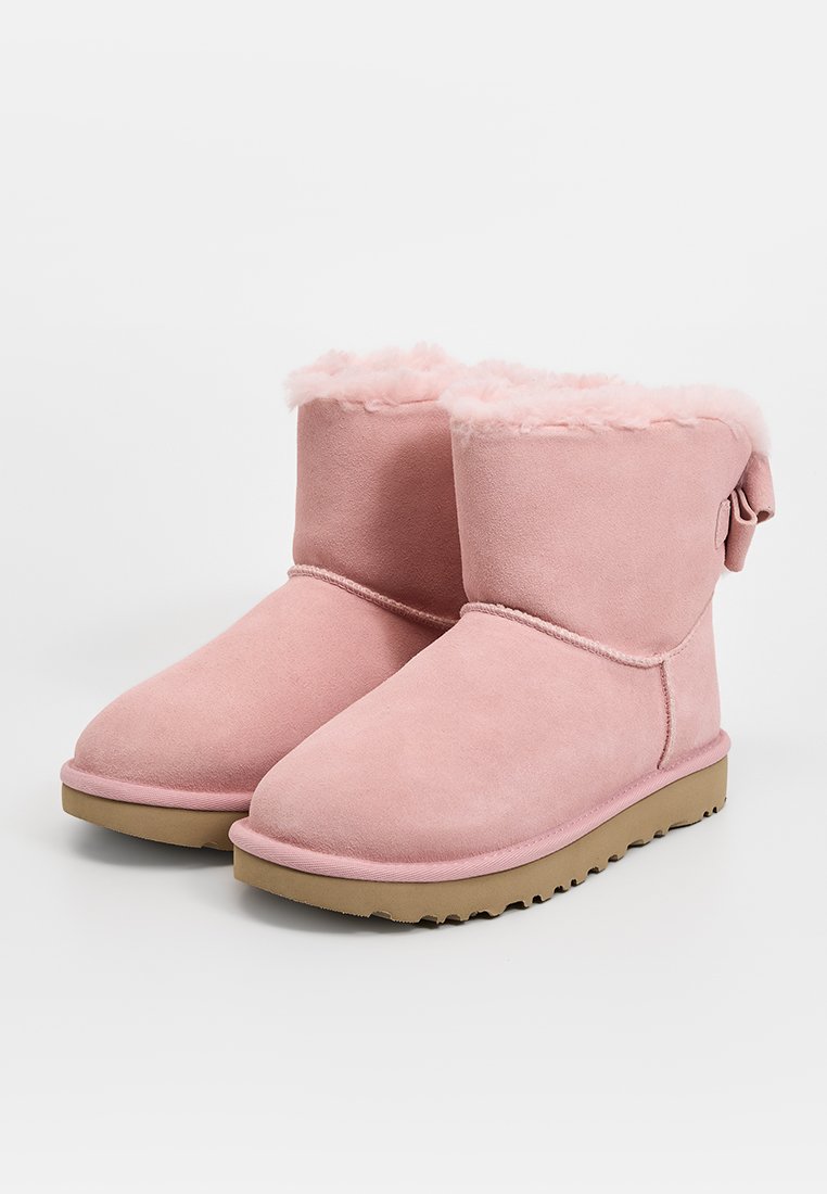 Rosa Wildleder Stiefeletten mit Kunstfellfutter und einem kleinen Schleifenakzent hinten. Flache Gummisohle mit strukturierter Lauffläche für besseren Halt.