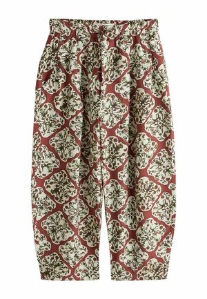 Voľné nohavice s elastickým pásom, zdobené celoplošným kvetinovým a viničovým vzorom v hnedej a zelenej farbe na červeno-hnedom podklade.