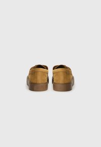 Brown suede slip-on shoes with a smooth texture and rubber soles. Features branding on the heel. Rounded shape with minimal design details.