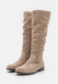 Bottes en suède beige jusqu'aux genoux avec un design plissé, des bouts ronds, des semelles plates et peu d'éléments en métal. Texture douce.