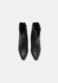 Zwarte leren enkelboots met een spitse neus en decoratieve stiksel. Bevat elastische zijpanelen en een gladde afwerking. Merkenlogo zichtbaar aan de binnenkant.