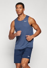 Mørkeblå atletisk tanktop med rund halsudskæring og et lille hvidt Nike-logo; parret med matchende mørkeblå shorts med et lignende logo.