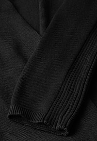 Tessuto a maglia nero, caratterizzato da costine testurizzate e una finitura liscia. I punti ritorti creano un motivo sottile lungo i bordi.