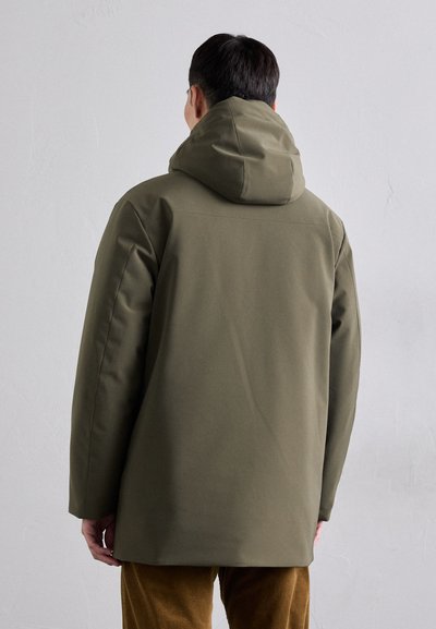Giacca verde oliva realizzata in un tessuto liscio e resistente all'acqua, dotata di cappuccio e di una vestibilità rilassata, senza chiusure o decorazioni visibili.