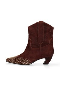 Stivale da cowboy in suede marrone con punta affilata, abbellito da borchie dorate sul davanti, con tacco basso e cuciture decorative.