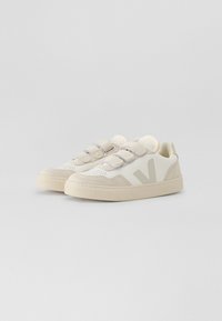 Beige sneakers med overdel i semsket skinn og mesh, med et fremtredende hvitt V-logo, borrelås og strukturerte gummisåler.