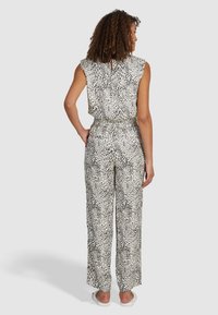 Combinaison imprimé léopard en tissu léger, dotée d'une ouverture en forme de goutte dans le dos, de manches gigot et d'une coupe décontractée avec des jambes larges.