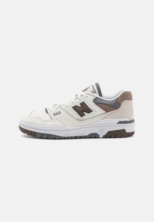 White and beige low-top New Balance 550 sneaker with brown "N" logo, perforated details, and gray and brown outsole, shown from the side.