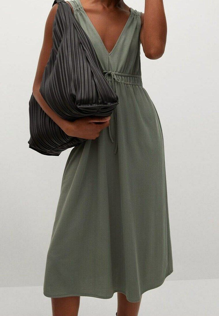 Olive green midi dress with a V-neck, adjustable tie waist, and shoulder straps. Paired with a large black pleated shoulder bag.