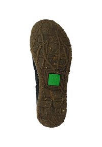 Černá podrážka boty s strukturovaným gumovým designem. Obsahuje hluboké drážky a zelené obdélníkové logo na zvýšené platformě.