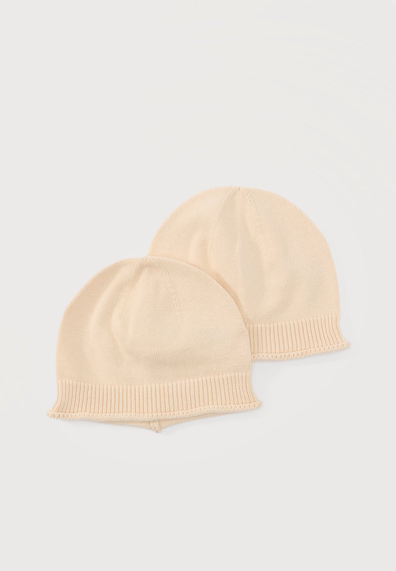 Δύο πανομοιότυπα μπεζ πλεκτά καπέλα μωρού με ριμπ άκρες, που βρίσκονται πάνω σε απλό ανοιχτόχρωμο φόντο.