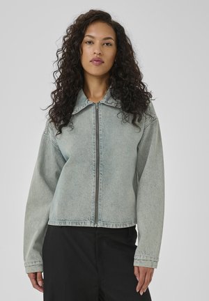 Light blue denim jacket with a zip front, pointed collar, long sleeves, and ribbed cuffs. Features a slightly cropped, relaxed fit.