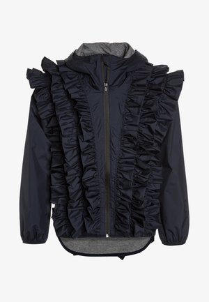 Tmavě modrá bunda s volánky podél přední části, zapínáním na zip a světle šedým vnitřkem. Má kapuci a elastické manžety.