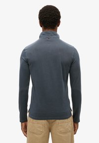 Mænds mørkeblå langærmet skjorte med høj krave og sidelommer. Glat tekstur med syninger ved kanten.