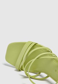 Sandal con tacco alto verde chiaro caratterizzato da una punta quadrata, design a più fasce, texture in pelle liscia e dettagli di cucitura sottili.
