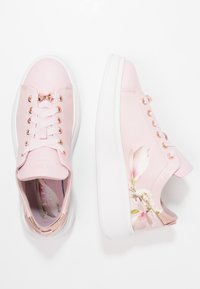 Baskets en cuir rose avec une semelle blanche, ornées de motifs floraux, d'œillets en or rose et de lacets contrastants. Des panneaux texturés ajoutent des détails.