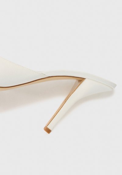 Sandal con tacco alto bianco, dalla texture liscia, con punta affusolata, lato aperto e tacco a stiletto sottile. Accentuata da una rifinitura beige.