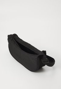 Borsa nera in tessuto con chiusura a zip, forma curva e tracolla regolabile. Presenta un branding discreto su un lato e una texture liscia e opaca.