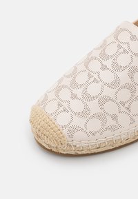 Scarpa di pelle con tomaia perforata caratterizzata da un motivo, di colore crema, e rifinitura in giuta intrecciata sulla punta. Design con punta arrotondata.